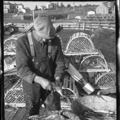 A man on a wharf scaling fish.